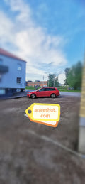 Röd bil bredvid bostadshus