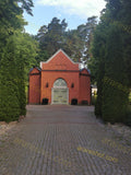 Historic Red Brick Chapel with Ornate Door and Lush Green Surroundings