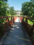 Scenic Red Metal Pedestrian Bridge Over Stream in Park