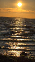 Sunset Over Rippling Water with Distant Land
