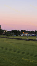 Green Field with Railway Tracks and Buildings