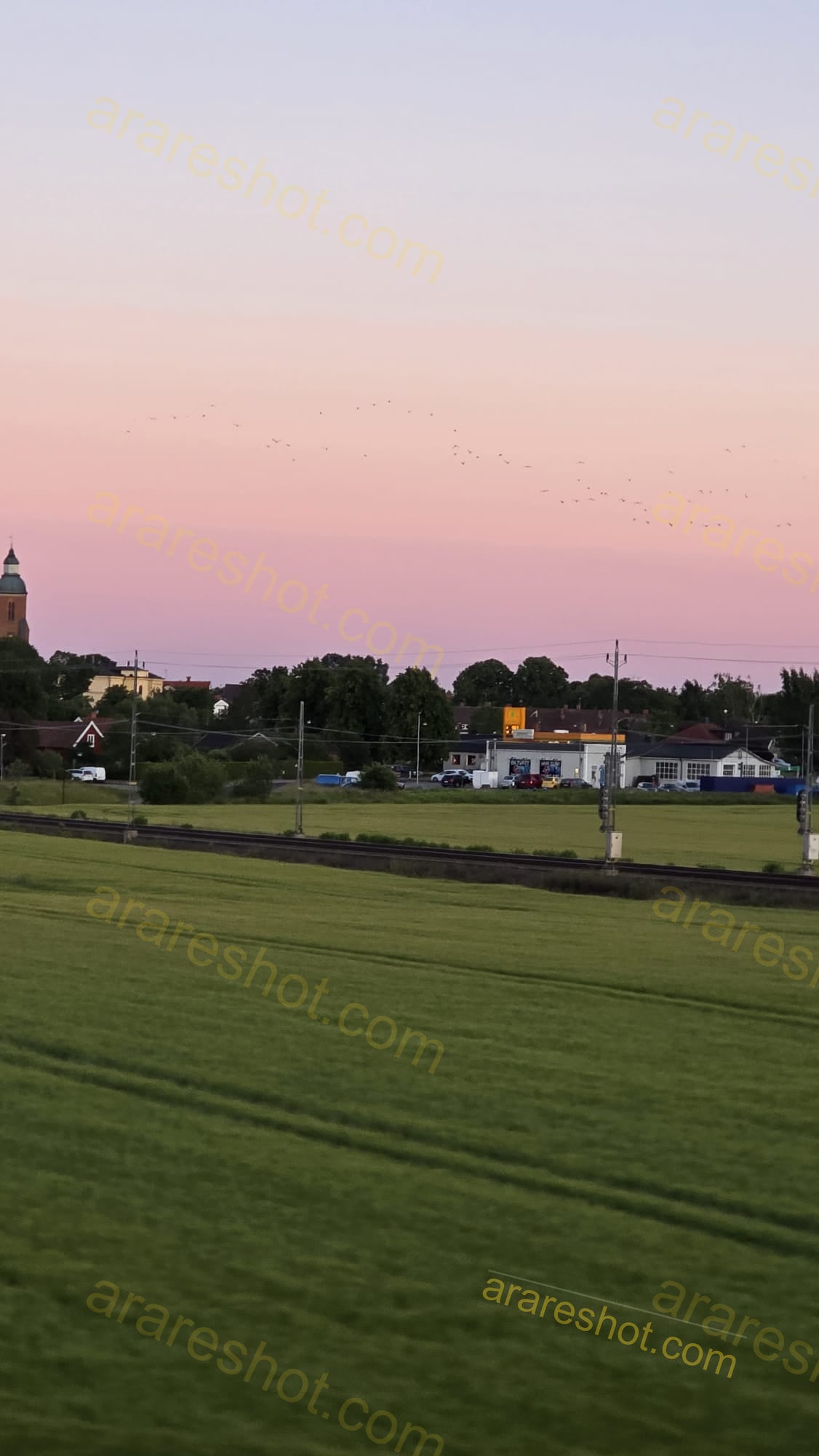 Green Field with Railway Tracks and Buildings
