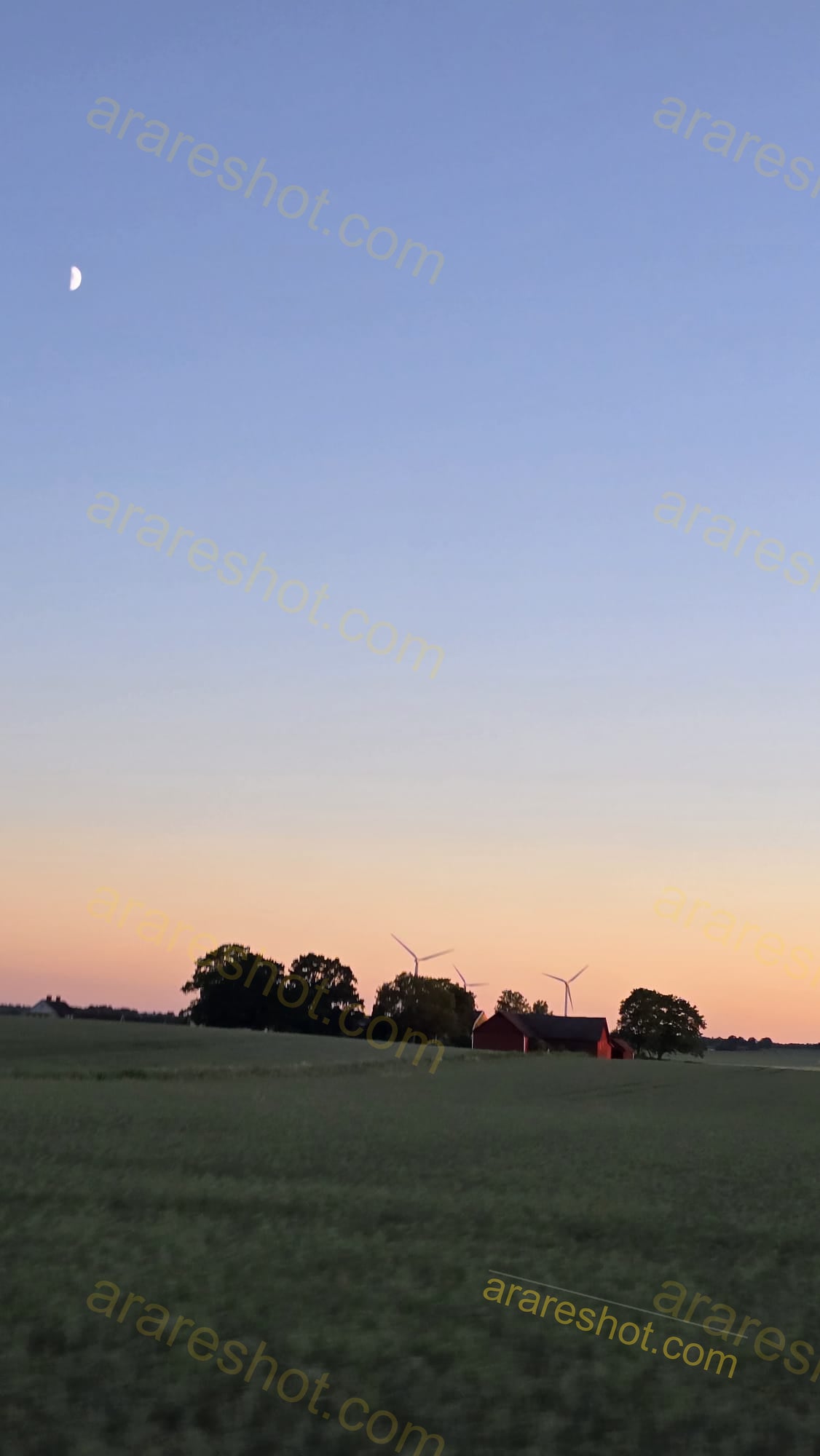 Green Field with Trees, Wind Turbines, and Red Barn at Sunset