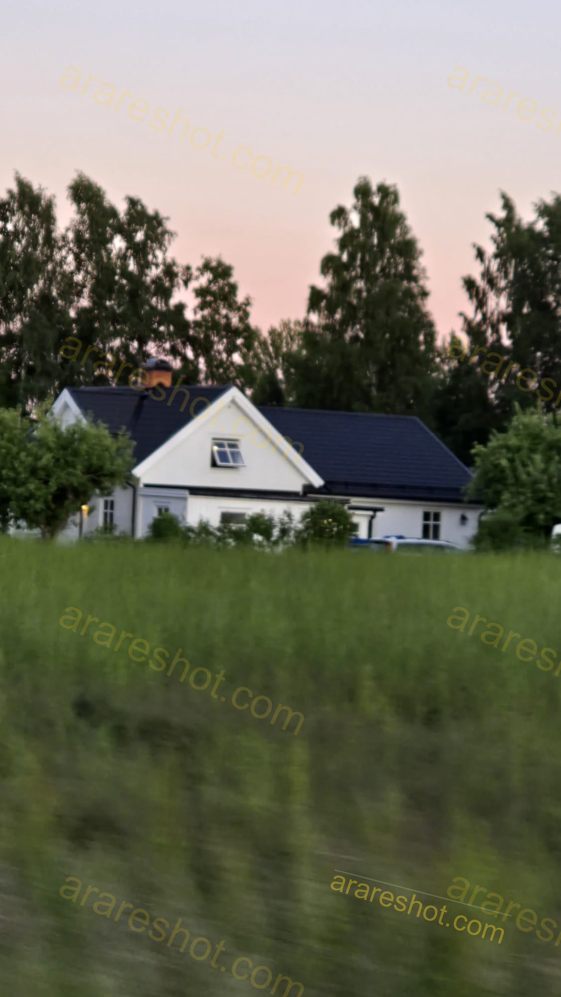 White House with Black Roof Behind Green Field