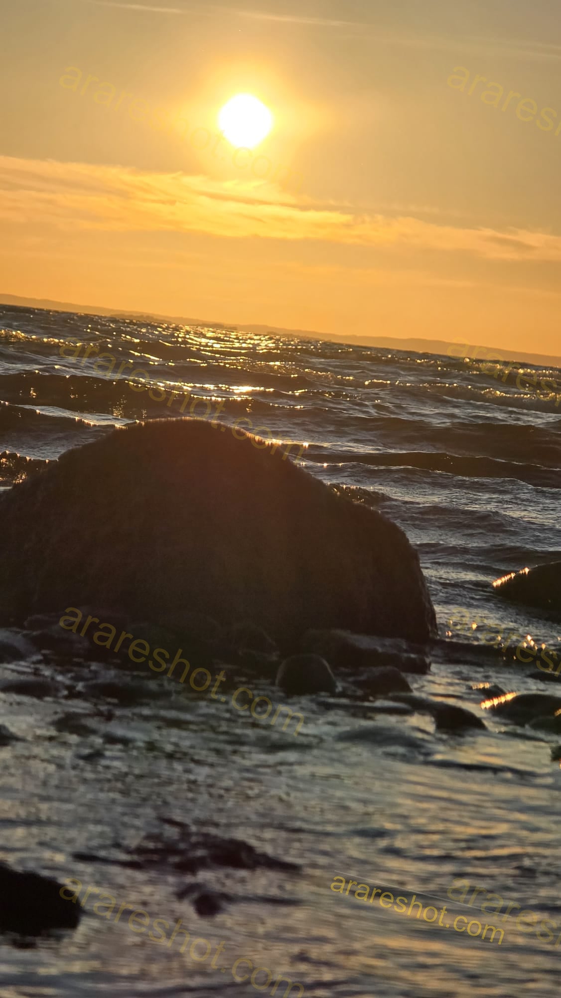 Sun Setting Over Ocean with Rocks