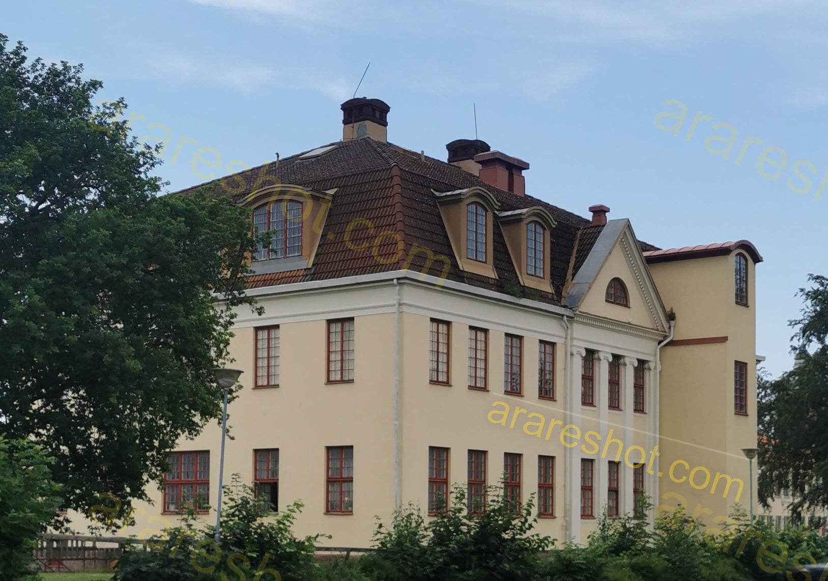Large Beige Building with Brown Roof and Multiple Windows