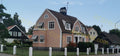 Two-Story Pink House with Dark Roof and White Fence