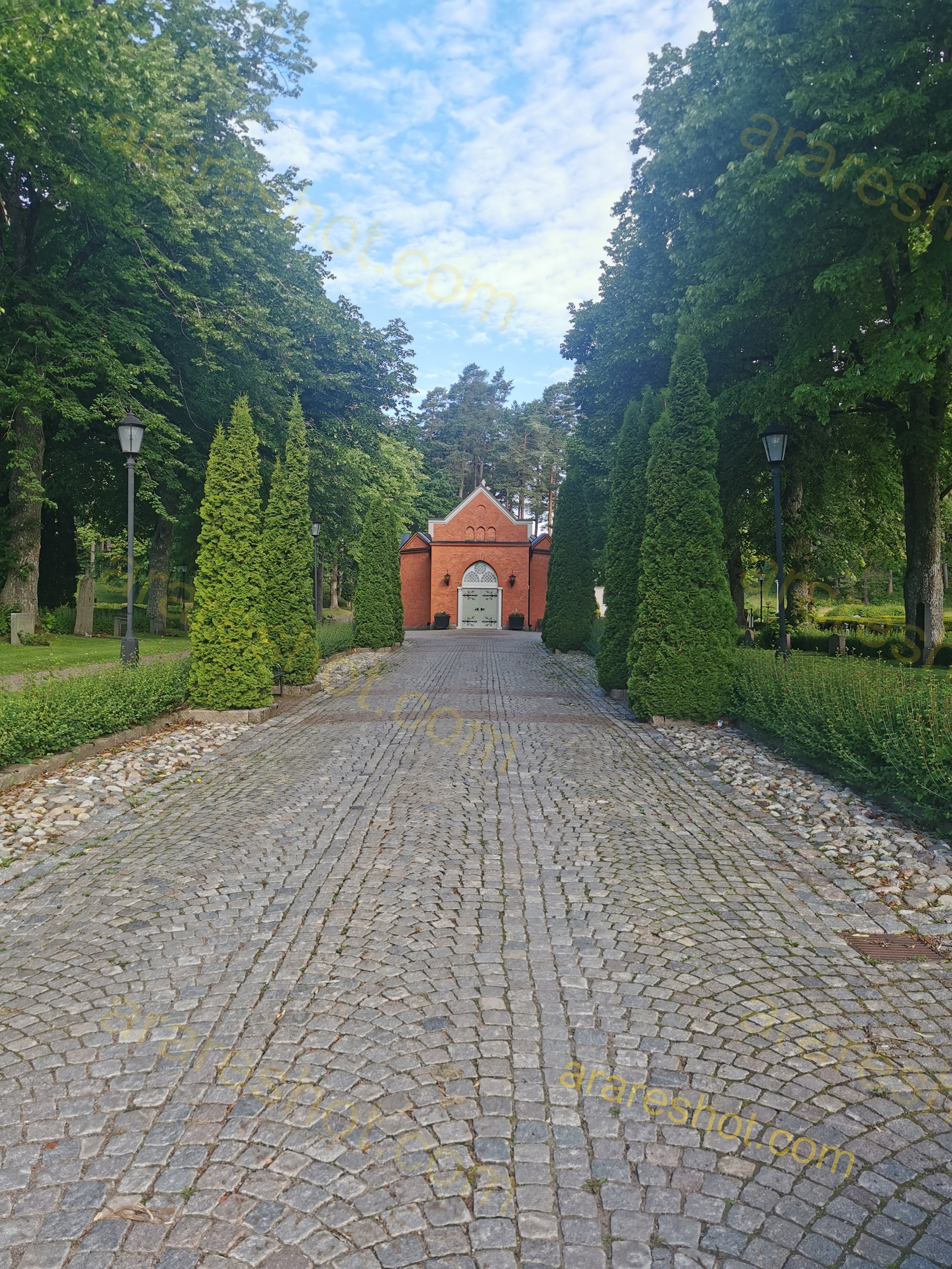 Cobbled Pathway Leading to Historic Brick Chapel Amid Lush Greenery